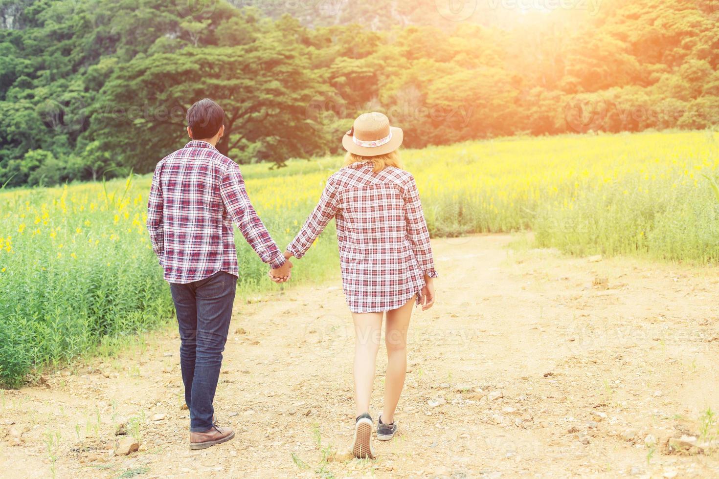 Young hipster couple relaxing in yellow flower field at summer. Enjoying with nature. photo