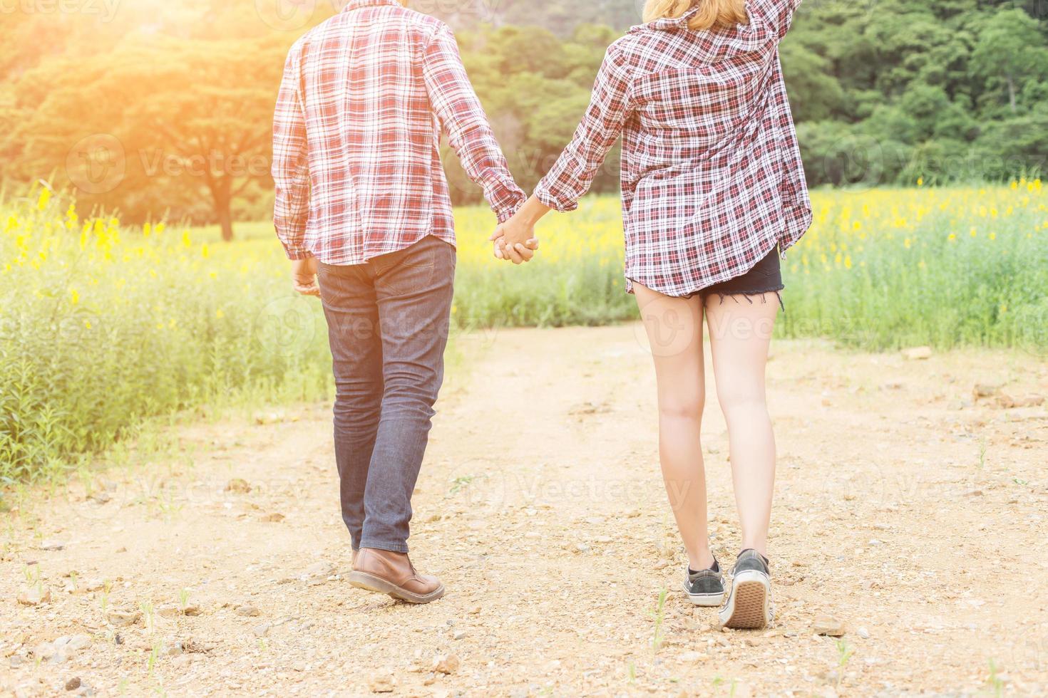 Young hipster couple relaxing in yellow flower field at summer. Enjoying with nature. photo