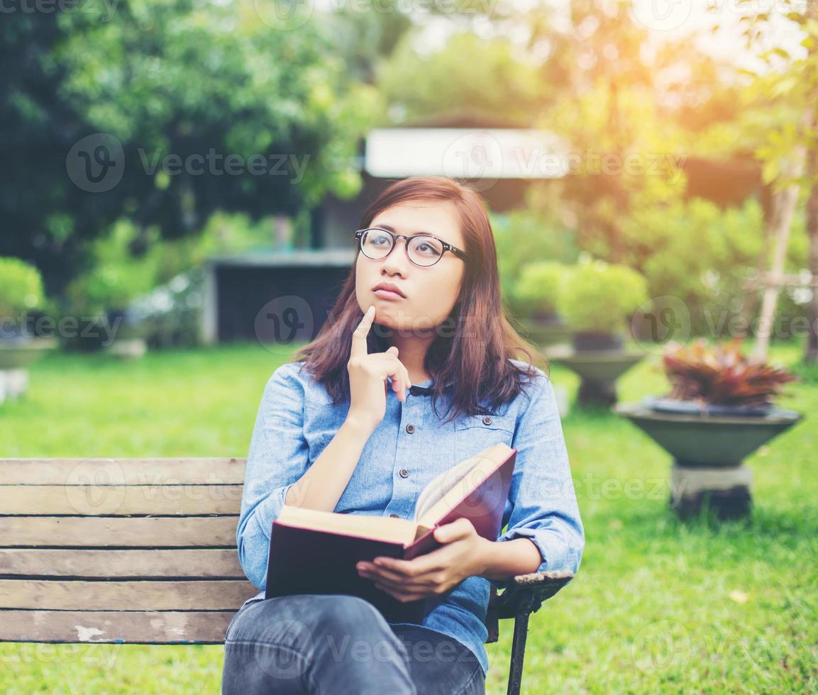 Hipster charming girl relaxing in the park while read book, Enjoy nature around. photo