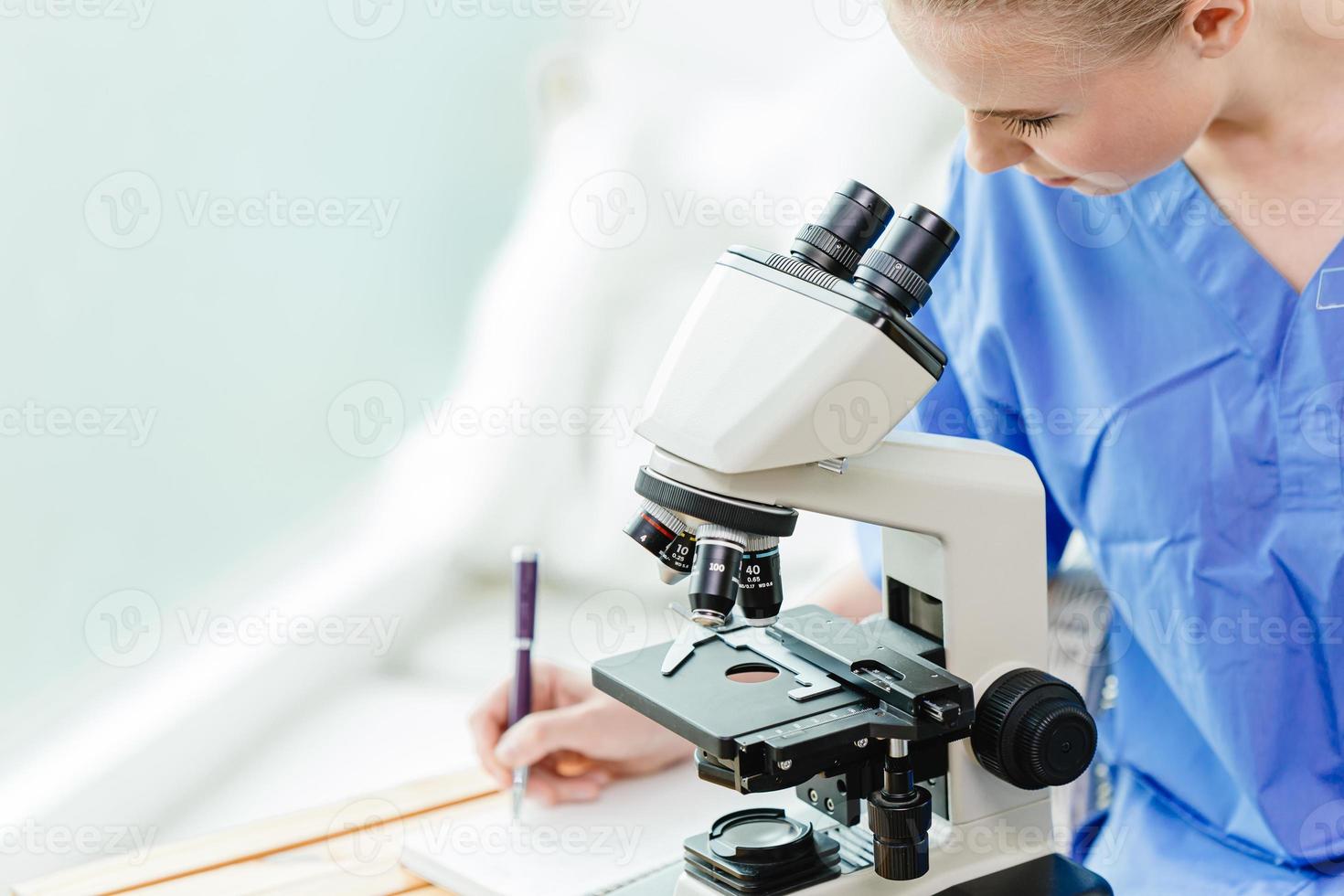 Young teen doctoral student in Medical university working study virus vaccine in school lab with microscope. photo