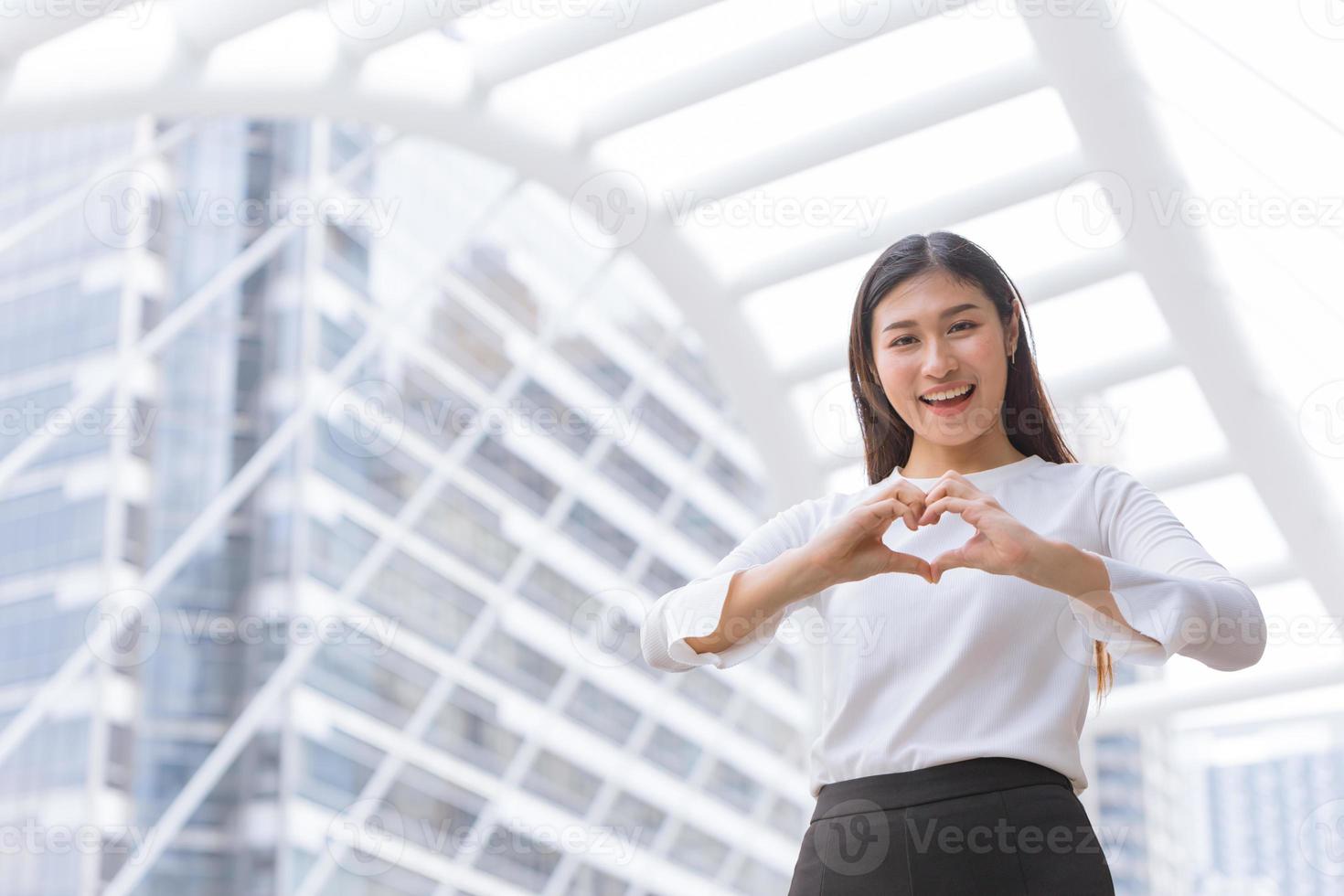 good business service from heart love care help and support customer working concept.happy woman staff show hand heart shape and smile. photo