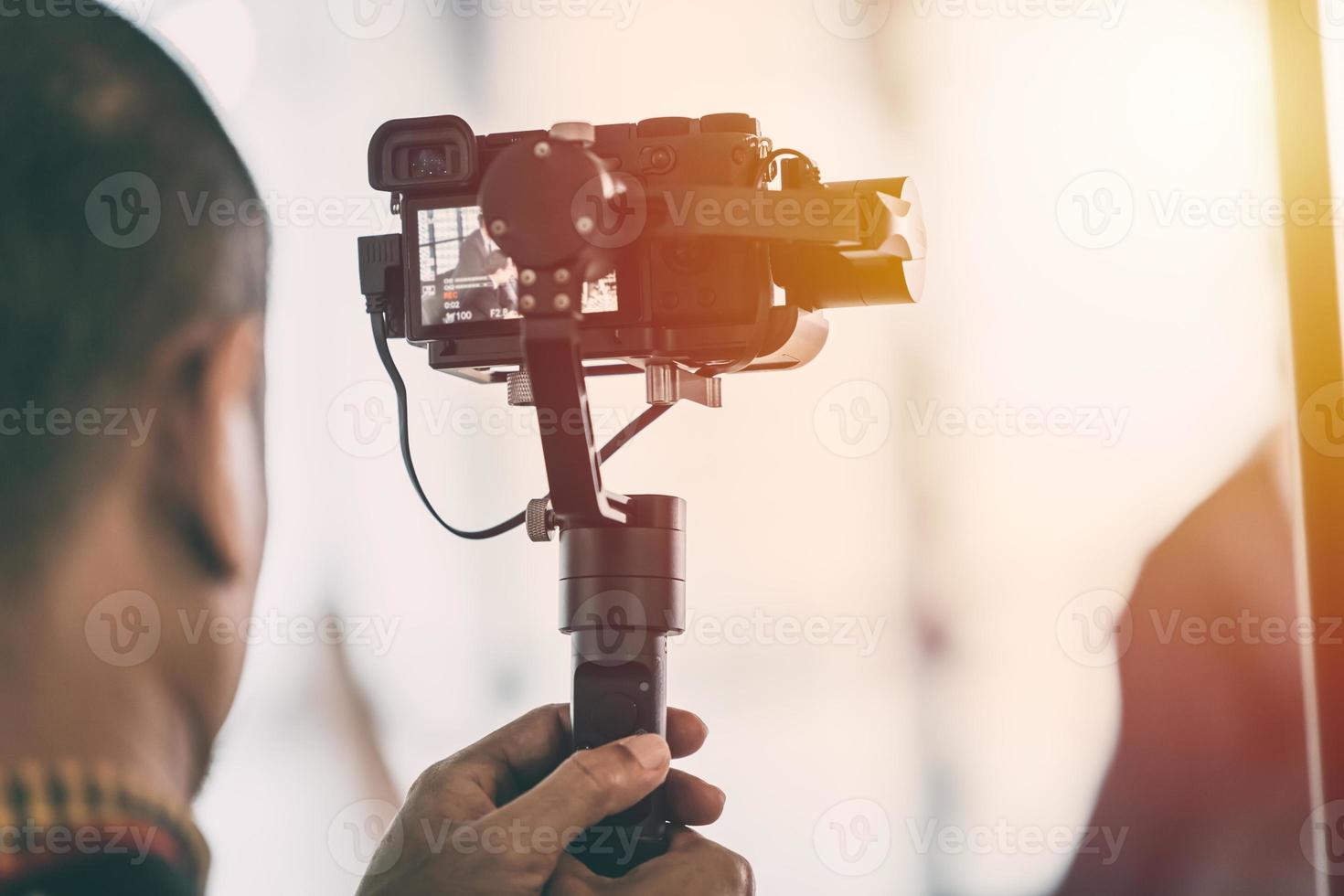 Videographer recording video with mirrorless digital camera on Gimbal Stabilization system photo
