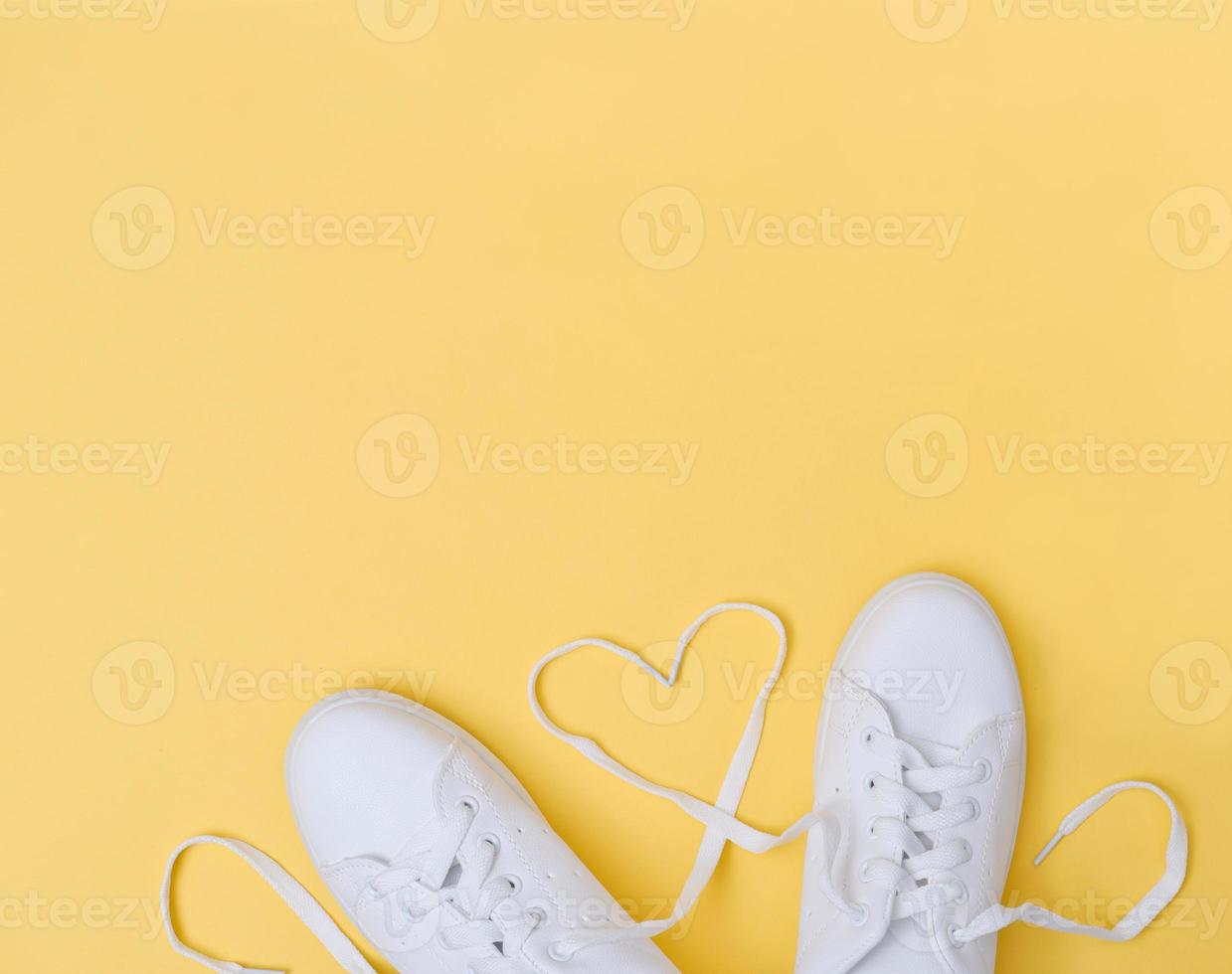 white sneackers with heart shaped laces on yellow background photo