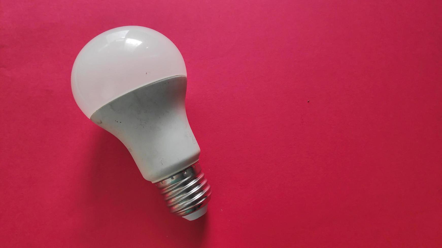 White light bulb on colored background in pastel colors. Minimalist concept, bright idea concept, isolated lamp photo