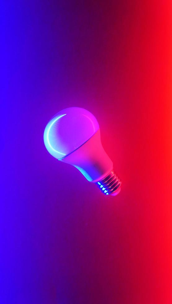 White light bulb on colored background in pastel colors. Minimalist concept, bright idea concept, isolated lamp photo