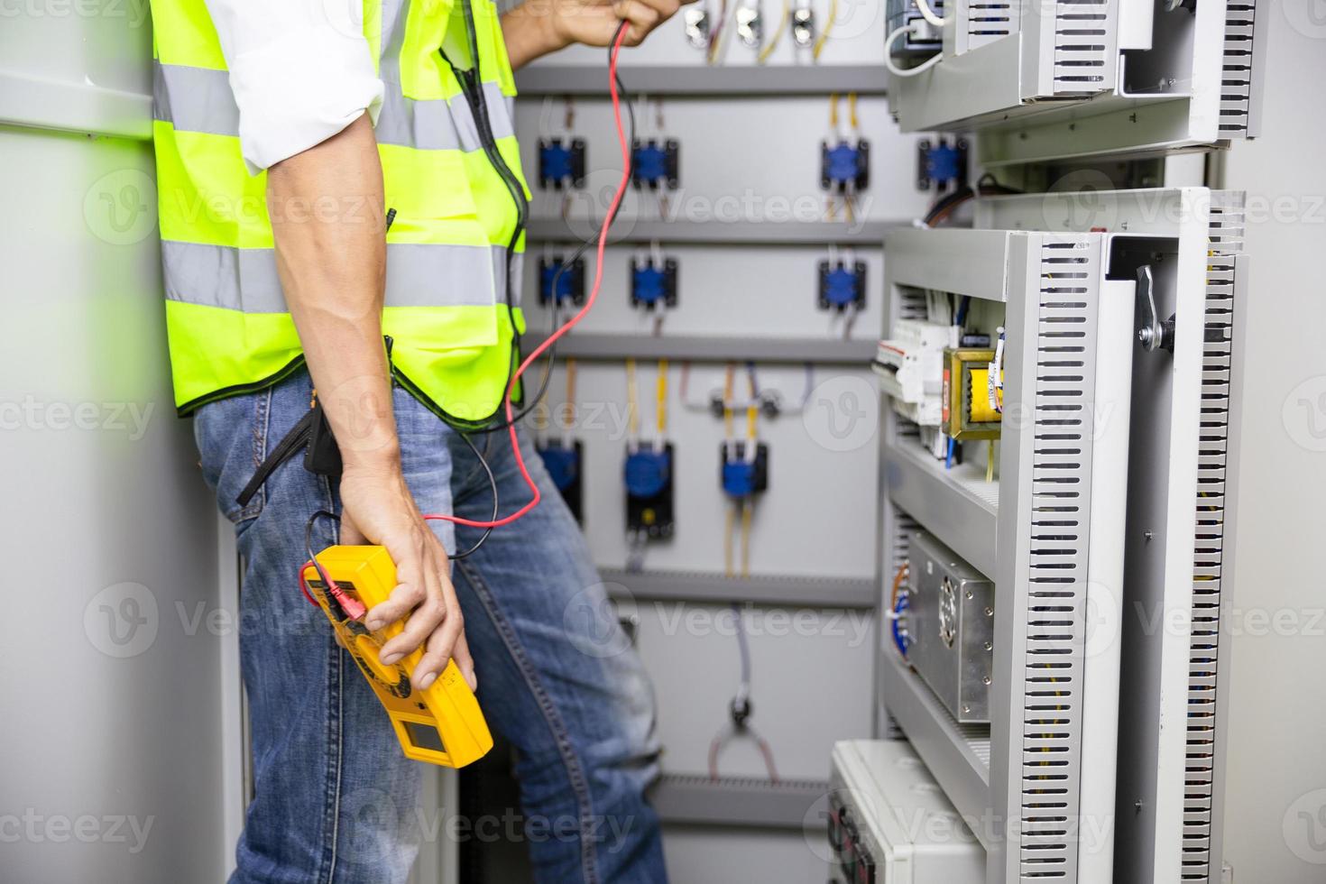 electricista trabajo ensayador medición voltaje y Actual de poder eléctrico  línea en eléctrico gabinete control, profesional hombre usos herramienta  puesta en marcha prueba o comprobación circuito para proteccion sistema.  27716561 Foto de