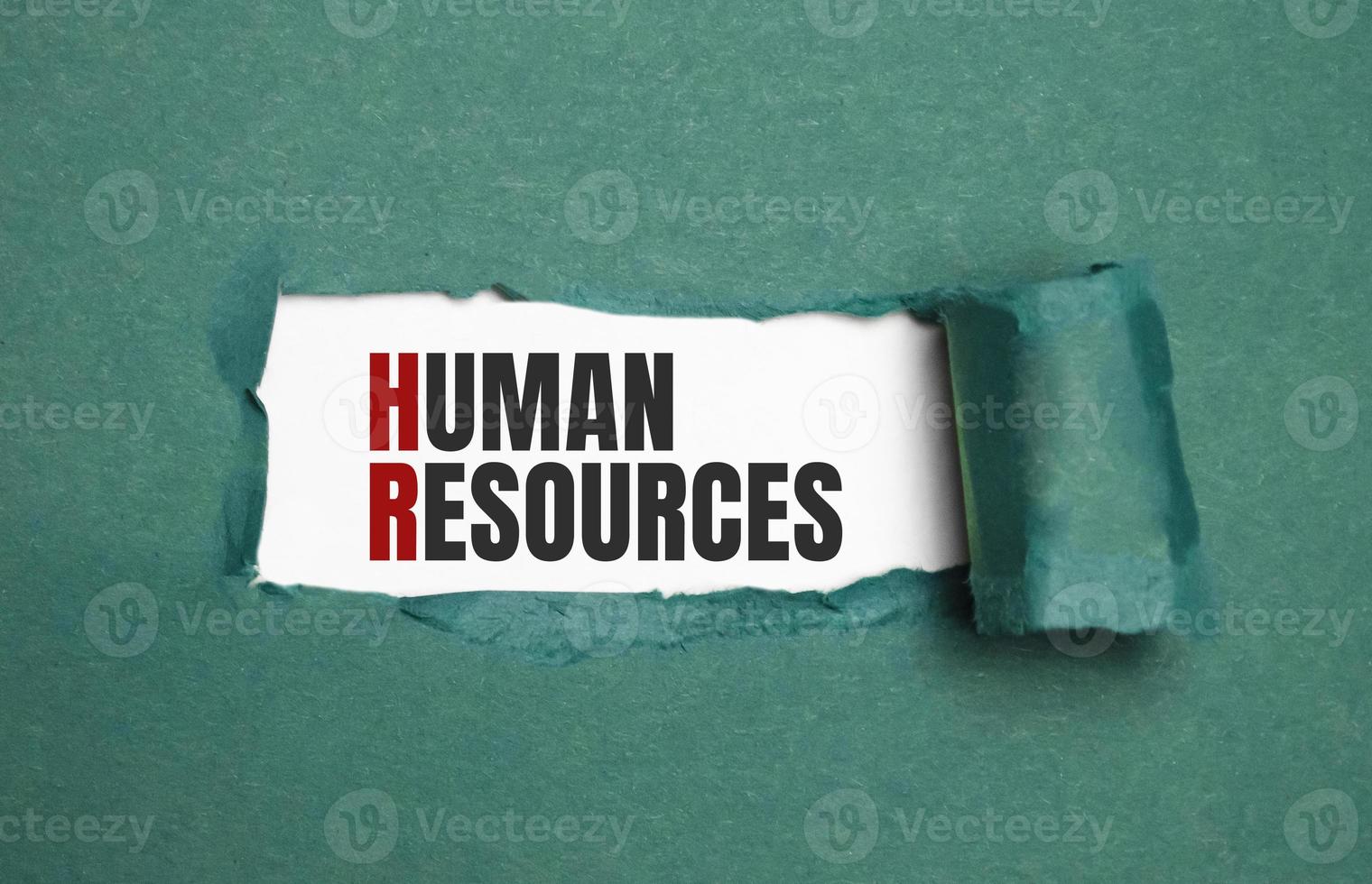 Torn green paper on white surface with HUMAN RESOURCES word. Business concept photo