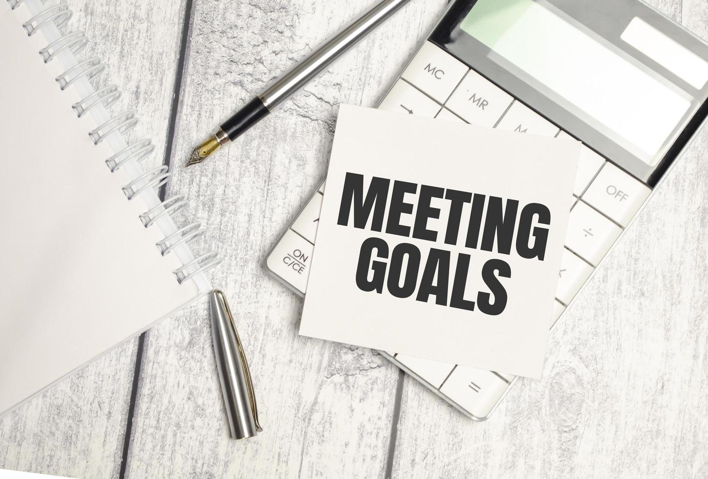 MEETING GOALS text on sticker with calculator, glasses and magnifier photo