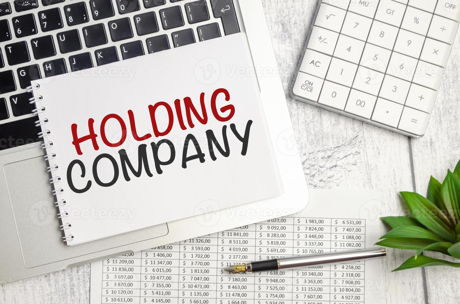 HOLDING COMPANY . text on white paper and laptop on wooden background photo