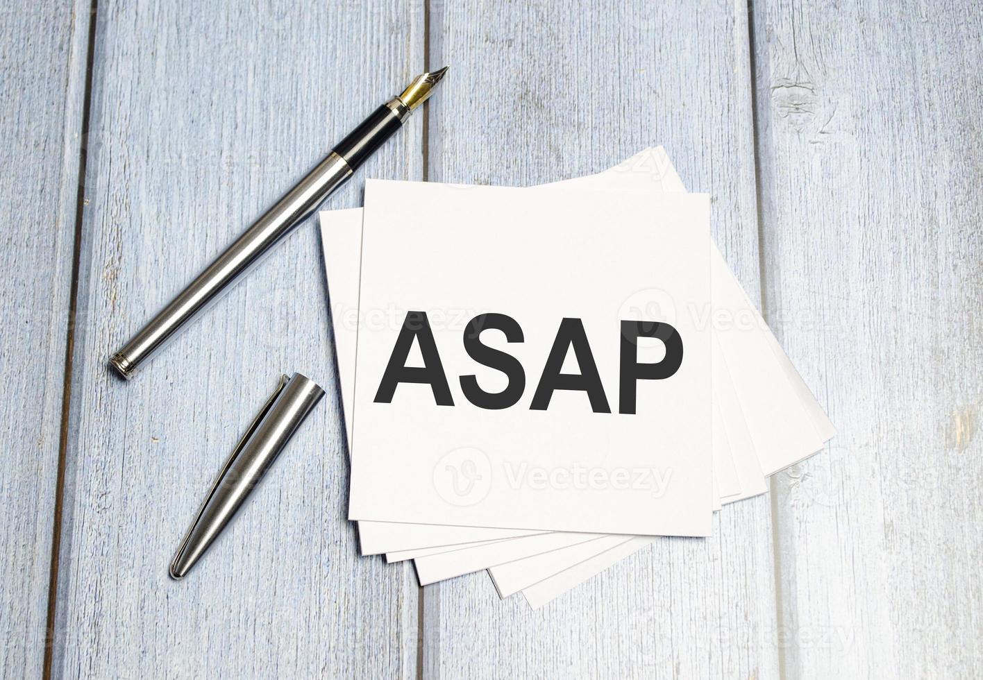 ASAP text on a sticky on notebook with pen photo