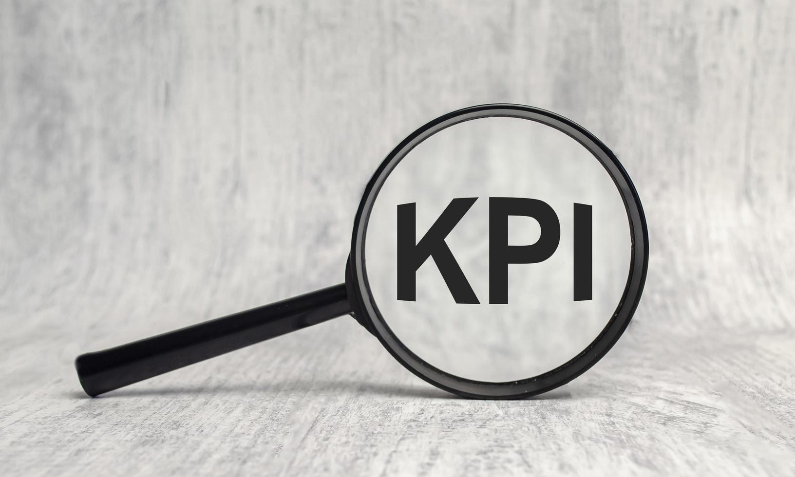 KPI acronym, word through magnifier on wooden background photo