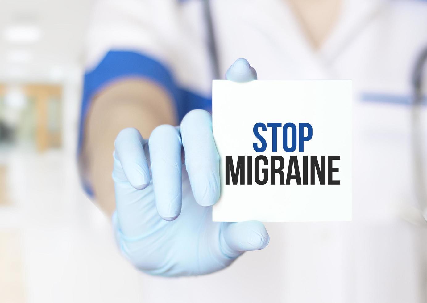 médico sosteniendo una tarjeta con texto detener la migraña, concepto médico foto