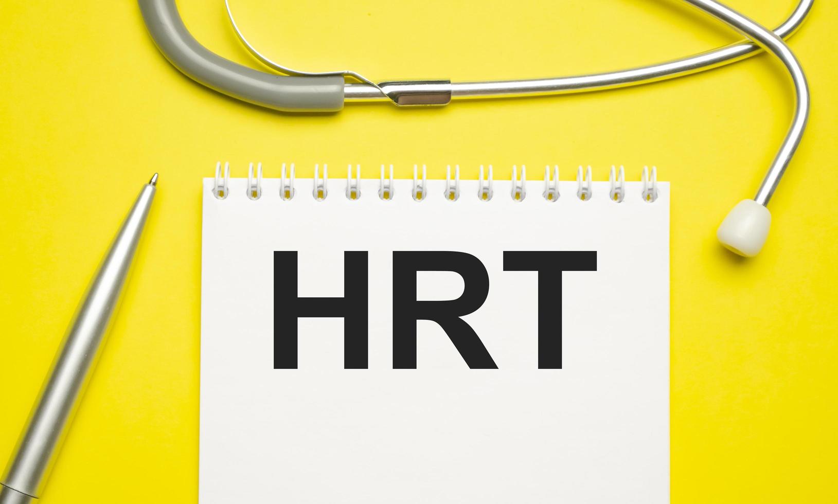 In the notebook is the text hrt and stethoscope, on yellow background photo