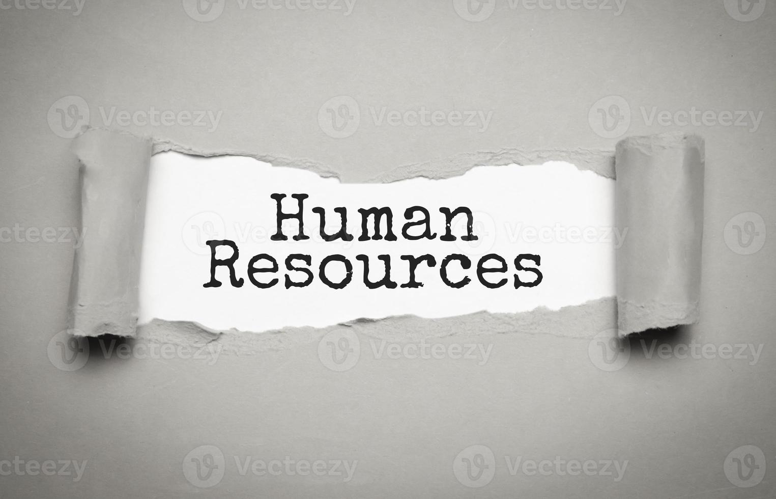 Torn grey paper on white surface with HUMAN RESOURCES word. Business concept photo