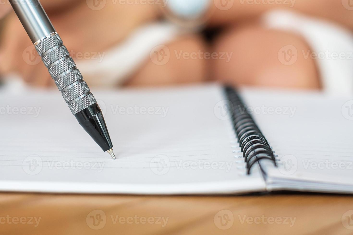 Businesswoman writing something on notebook in office or cafe, hand of woman holding pen with signature on paper report. business concepts photo