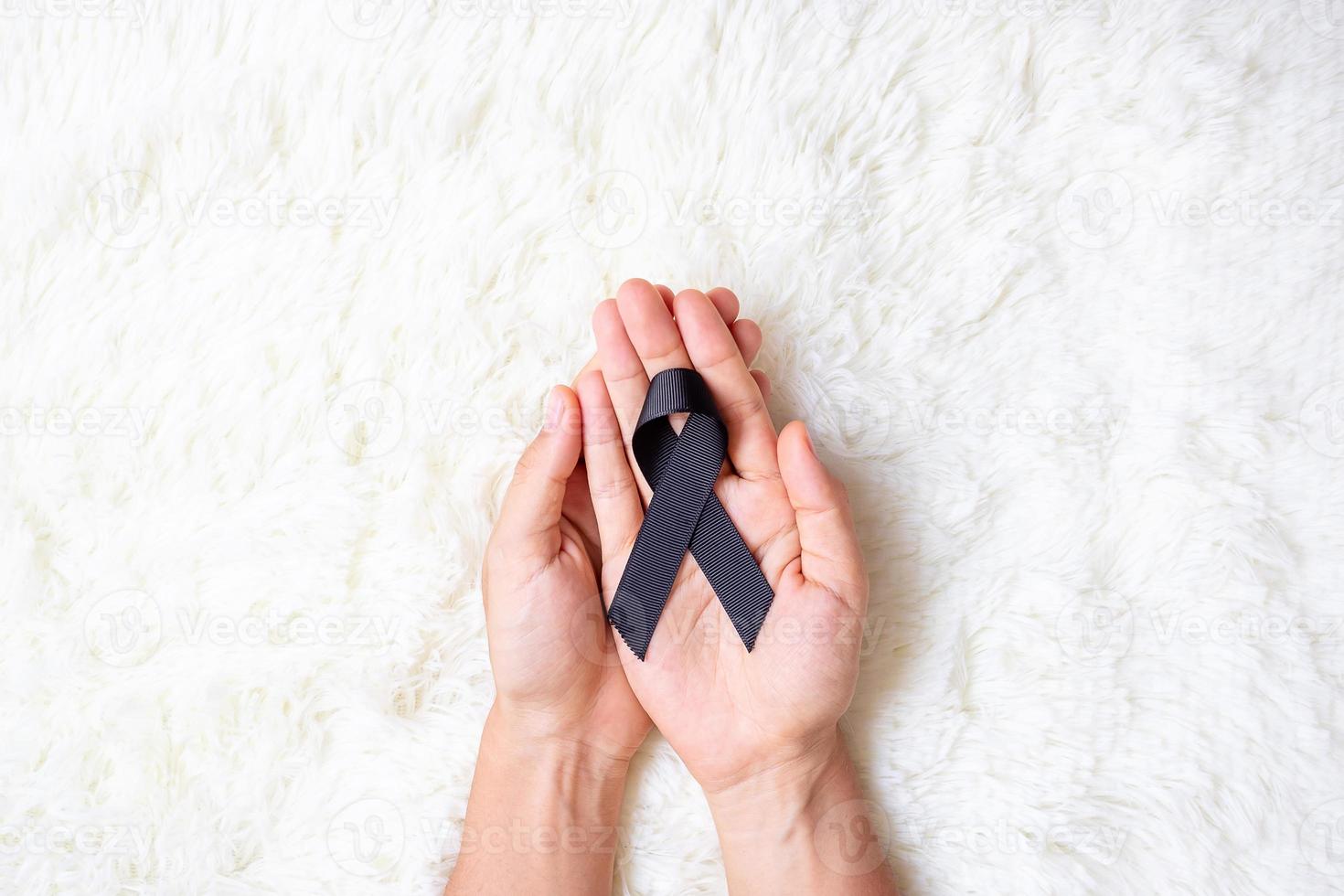 Melanoma and skin cancer, Vaccine injury awareness month and rest in peace concepts. Man holding black Ribbon on white bed background photo