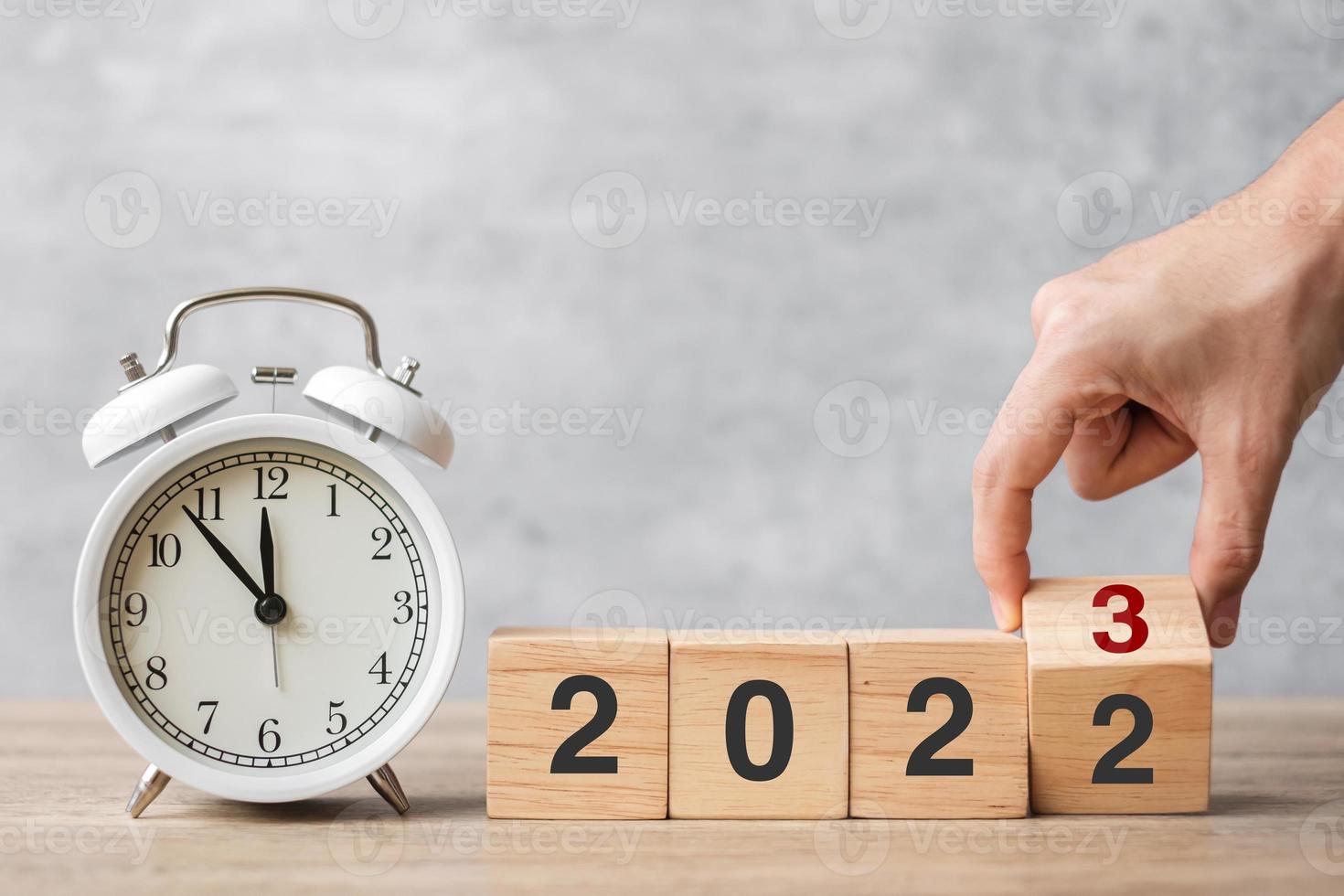 Happy New Year with vintage alarm clock and hand flipping 2022 change to 2023 block. Christmas, New Start, Resolution, countdown, Goals, Plan, Action and Motivation Concept photo