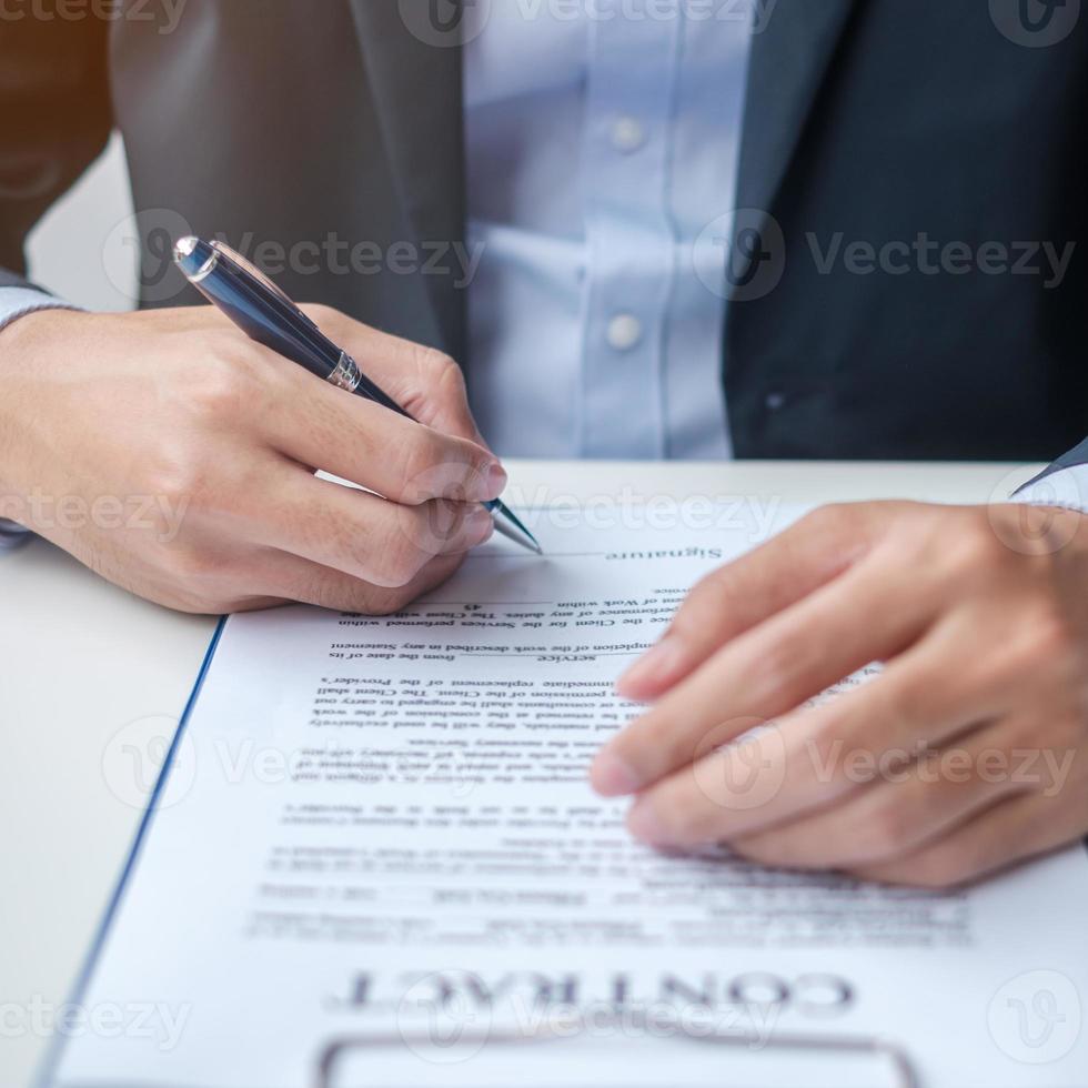 Businessman signing on contract documents after reading, man holding pen and approve on business report. Contract agreement, partnership and deal concepts photo