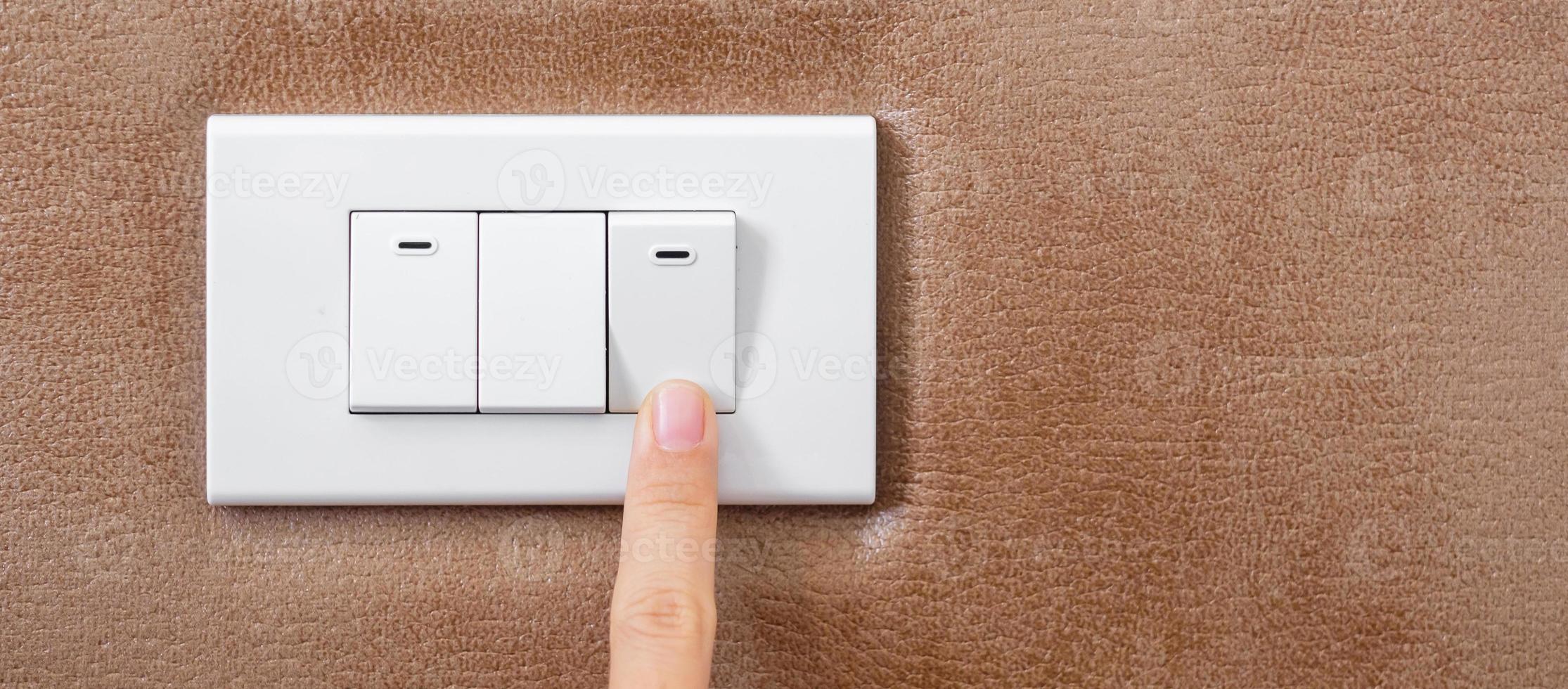 finger turn on or off on light switch on wall at home. Energy Saving, power, electrical and lifestyle concepts photo