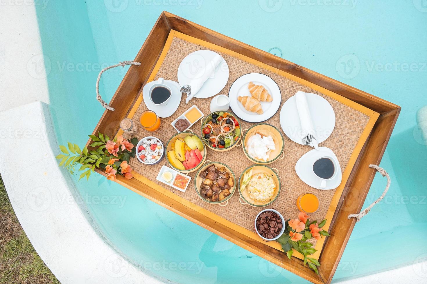 Floating Breakfast tray in swimming pool at luxury hotel or tropical resort villa, fruits, croissant, coffee, and orange juice. Exotic summer, relaxation, tropical travel and vacation concept photo