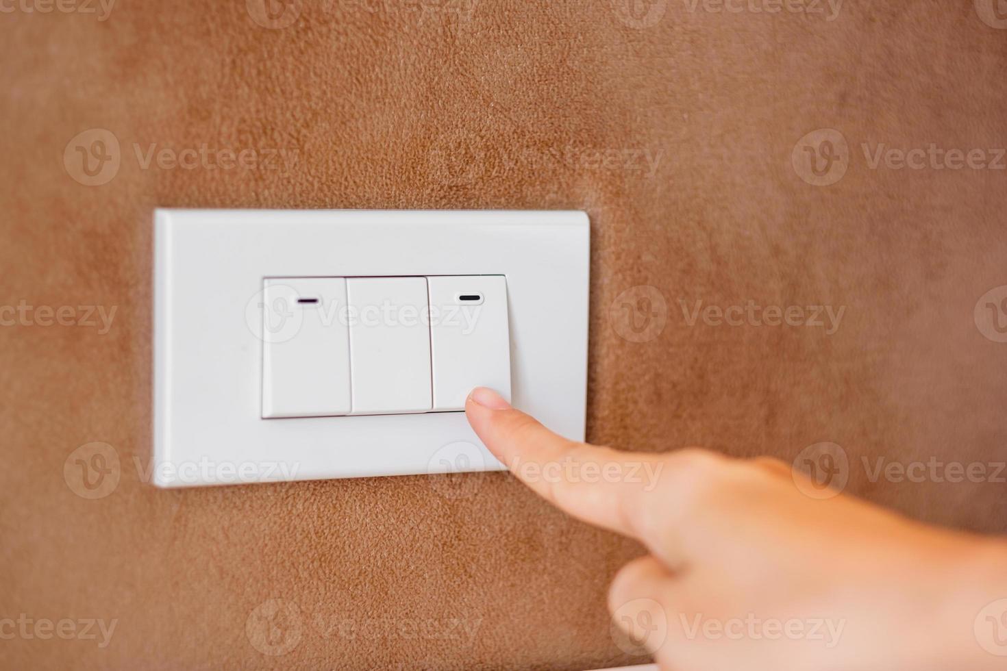 finger turn on or off on light switch on wall at home. Energy Saving, power, electrical and lifestyle concepts photo
