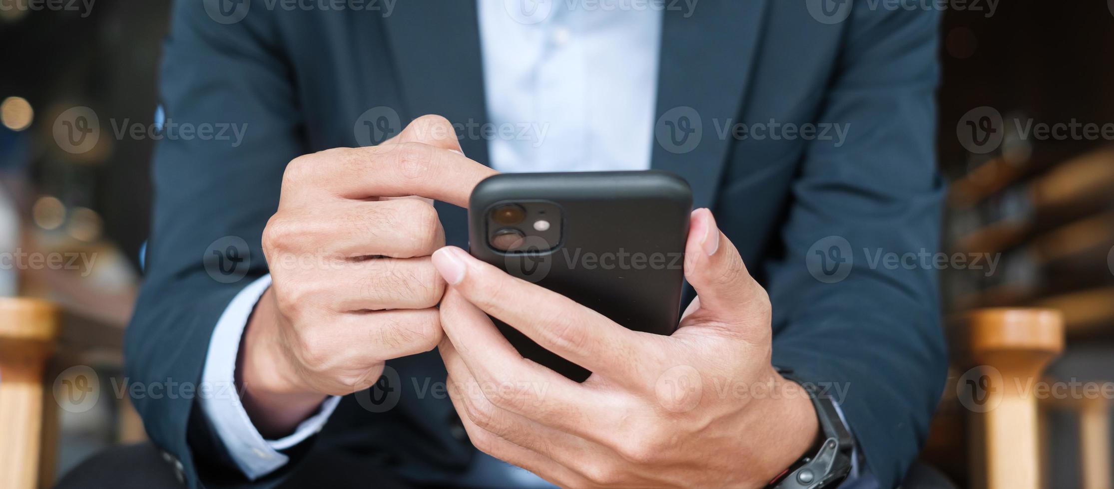 young Businessman in suit holding and using smartphone for sms messages, man typing touchscreen mobile phone in office or cafe. business, lifestyle, technology and Social media network concept photo