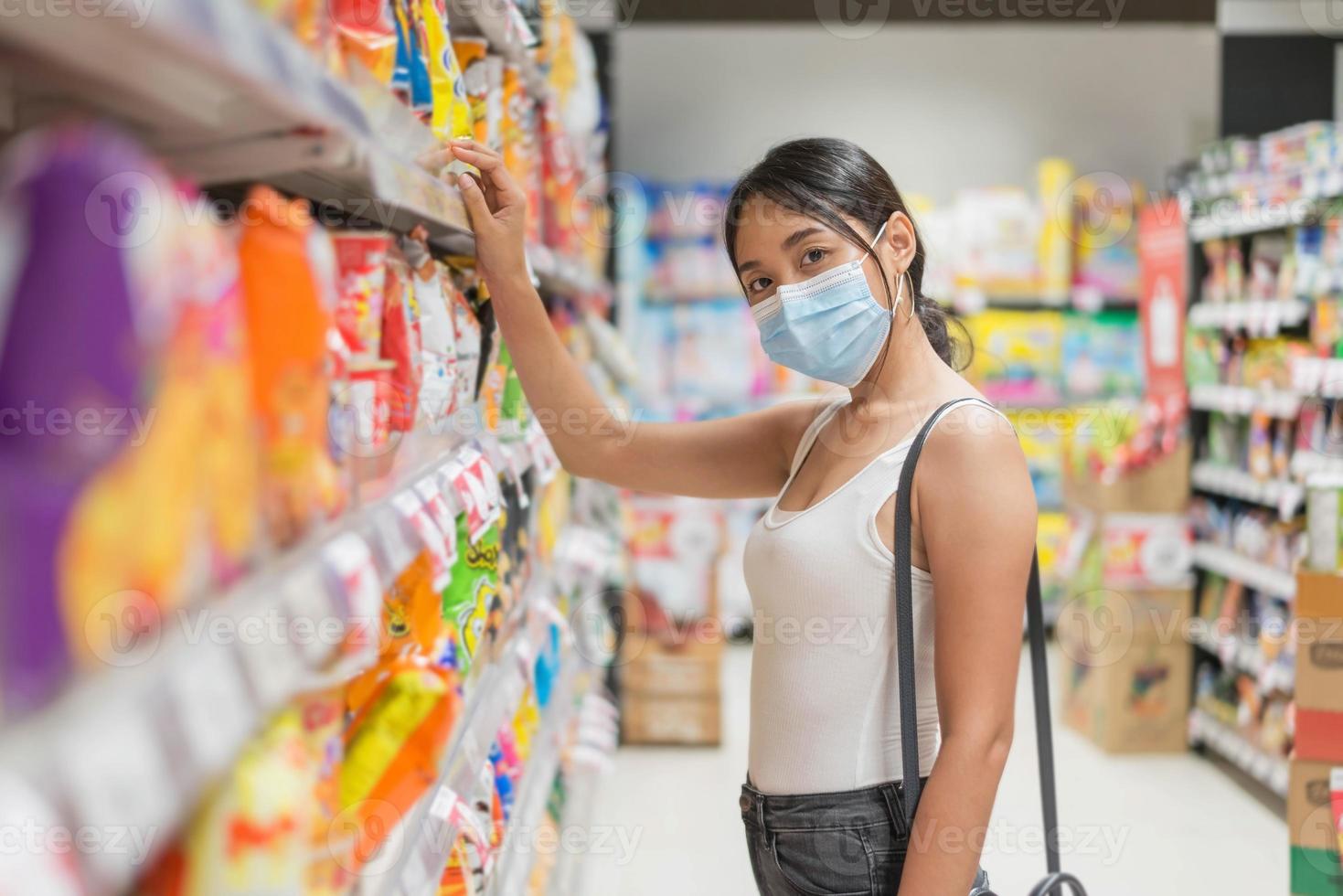 mujer asiática con mascarilla comprando en el supermercado. concepto de seguridad y pandemia de coronavirus. nuevo estilo de vida normal. foto