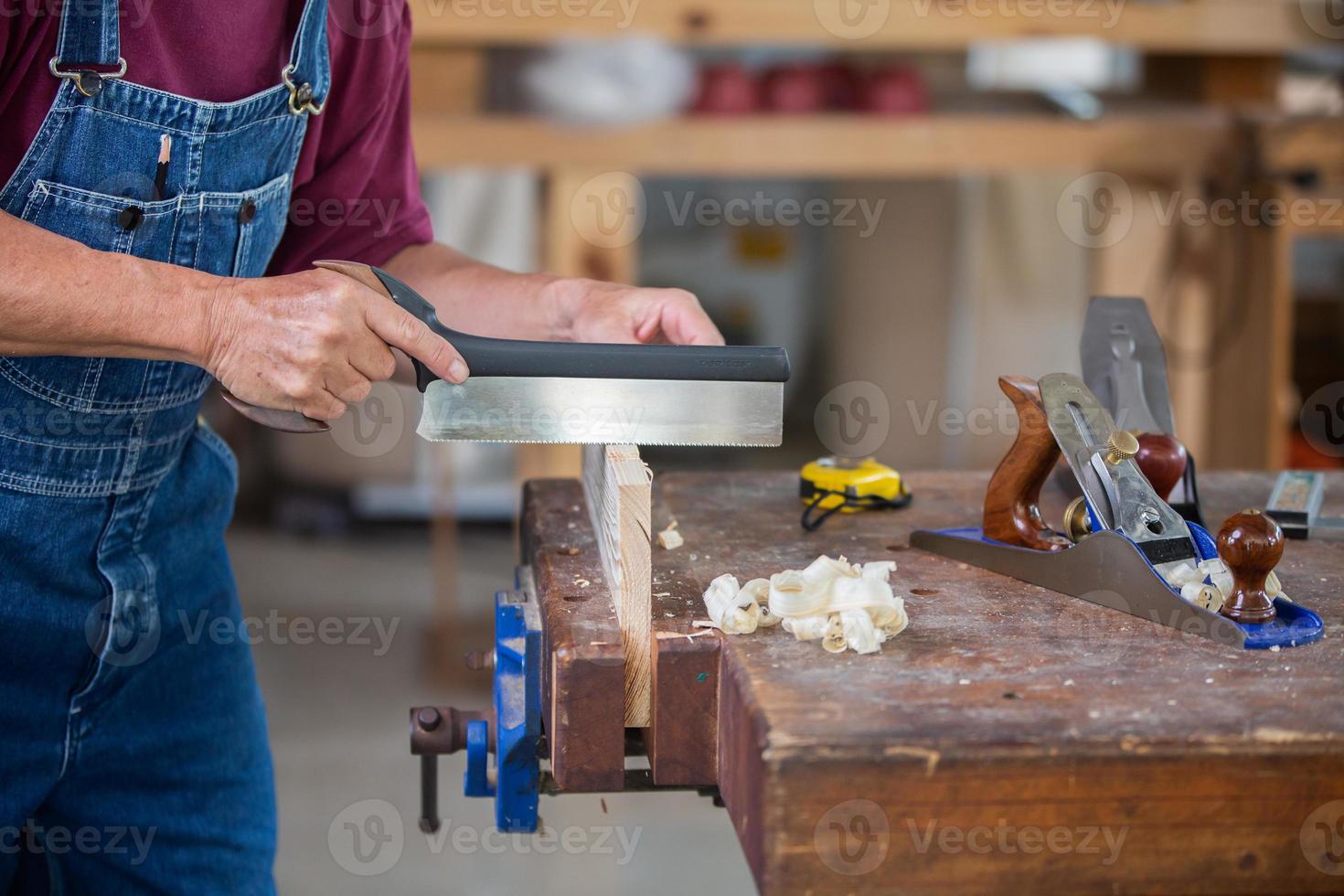A carpenter works with equipment on a wooden table in a carpentry shop. photo