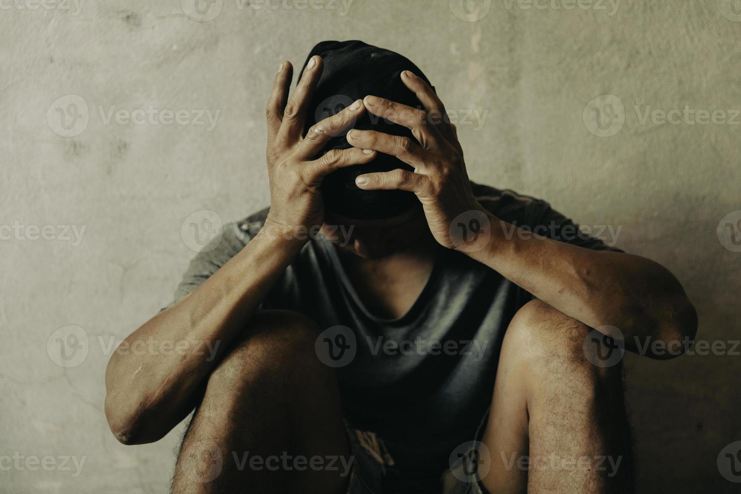 A drug addicted homeless man sitting alone and depressed in an abandoned house feeling anxious and lonely. photo