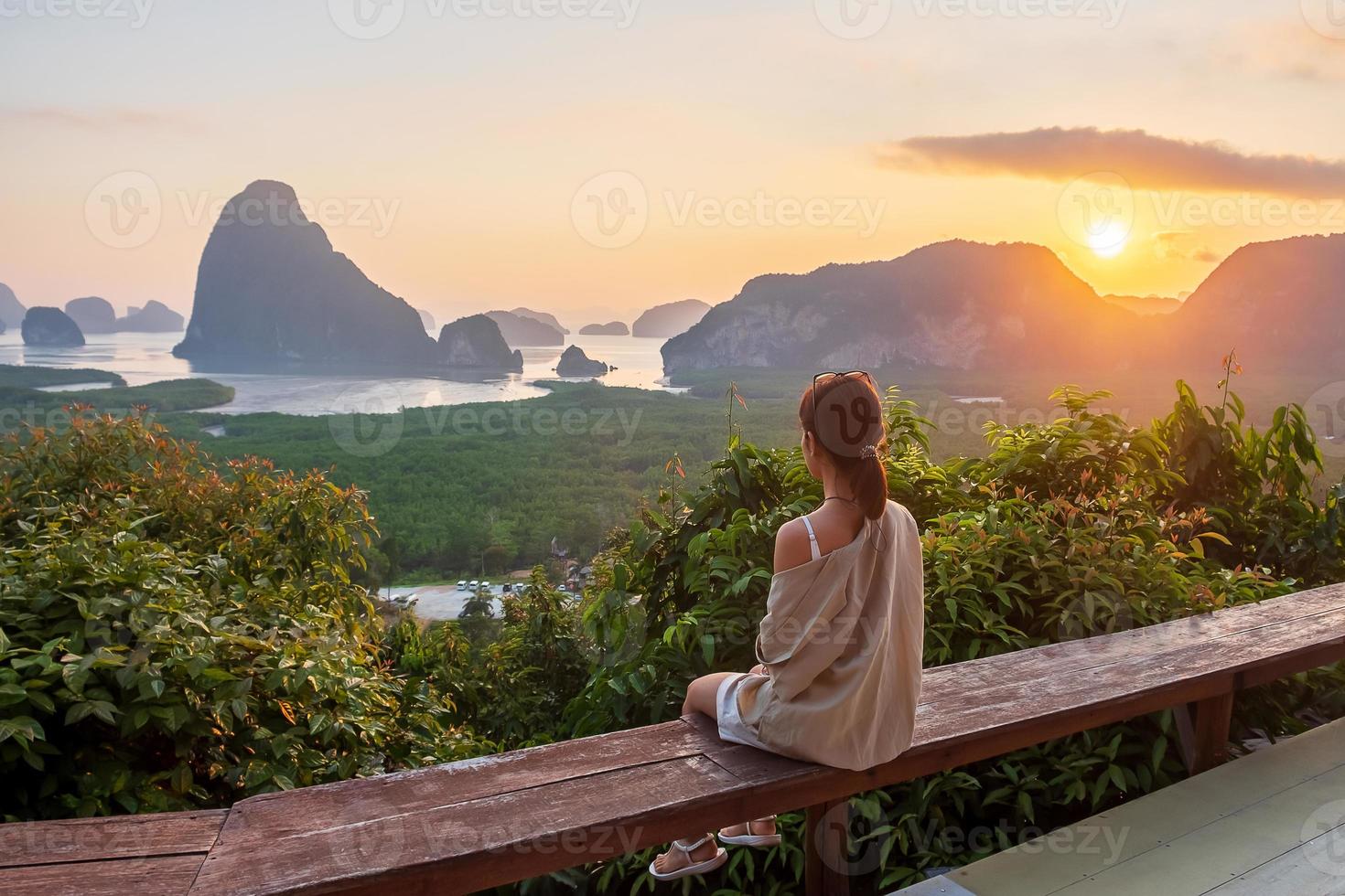 mujer viajera feliz disfruta del punto de vista de la bahía de phang nga, turista sola sentada y relajándose en samet nang she, cerca de phuket en el sur de tailandia. concepto de viaje, viaje y vacaciones de verano del sudeste asiático foto