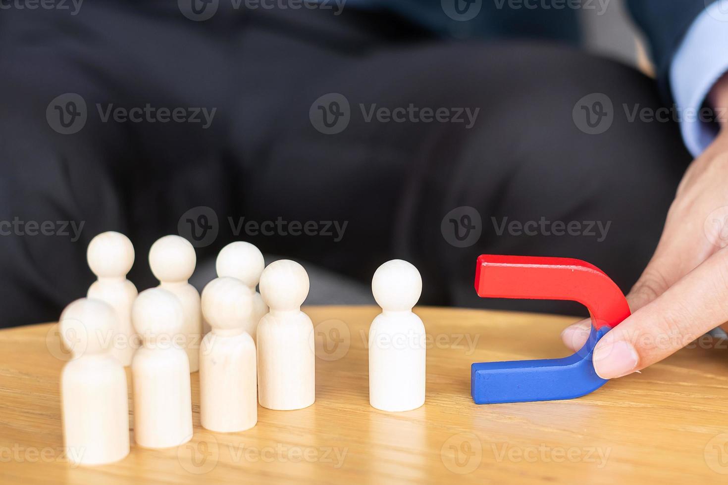 Businessman hand holding magnet and pulling man wooden figure from the crowd employee. Business, Human resource management, Recruitment, Teamwork, strategy, toxic people and leadership Concepts photo