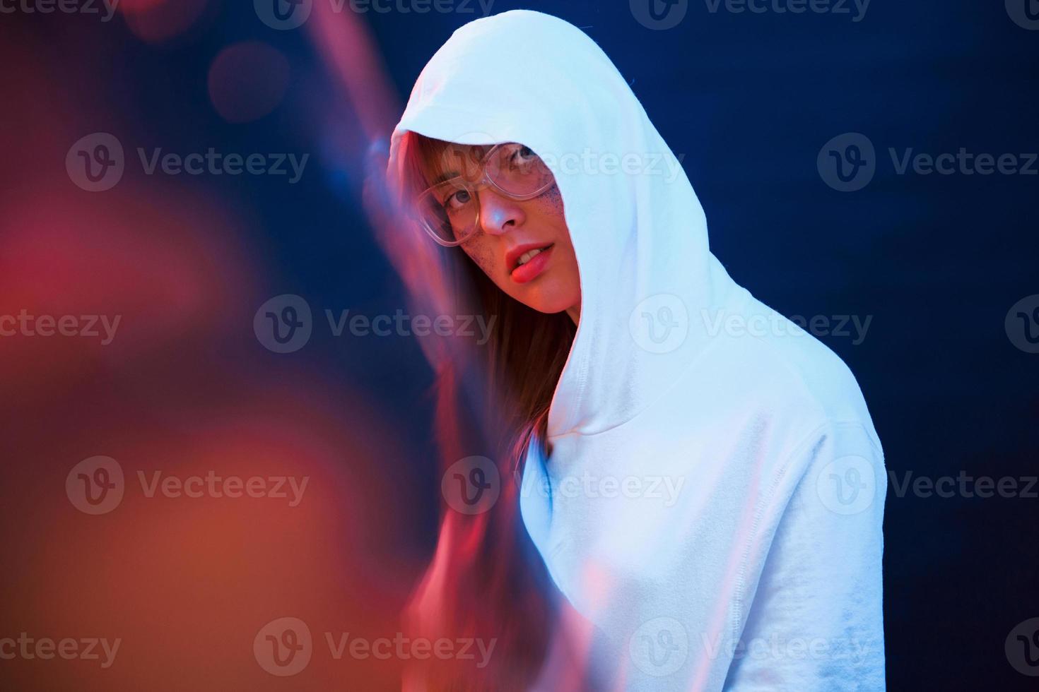 Looking at you with interest. Studio shot in dark studio with neon light. Portrait of young girl photo