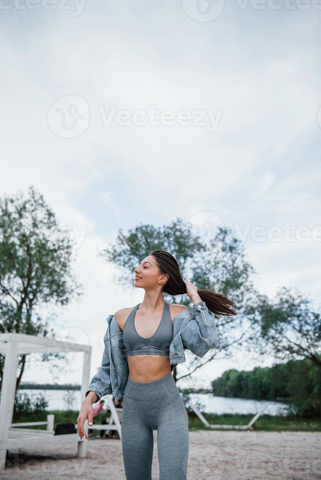 Portrait of cute girl. Positive woman in sportive clothes enjoying nature on the beach photo