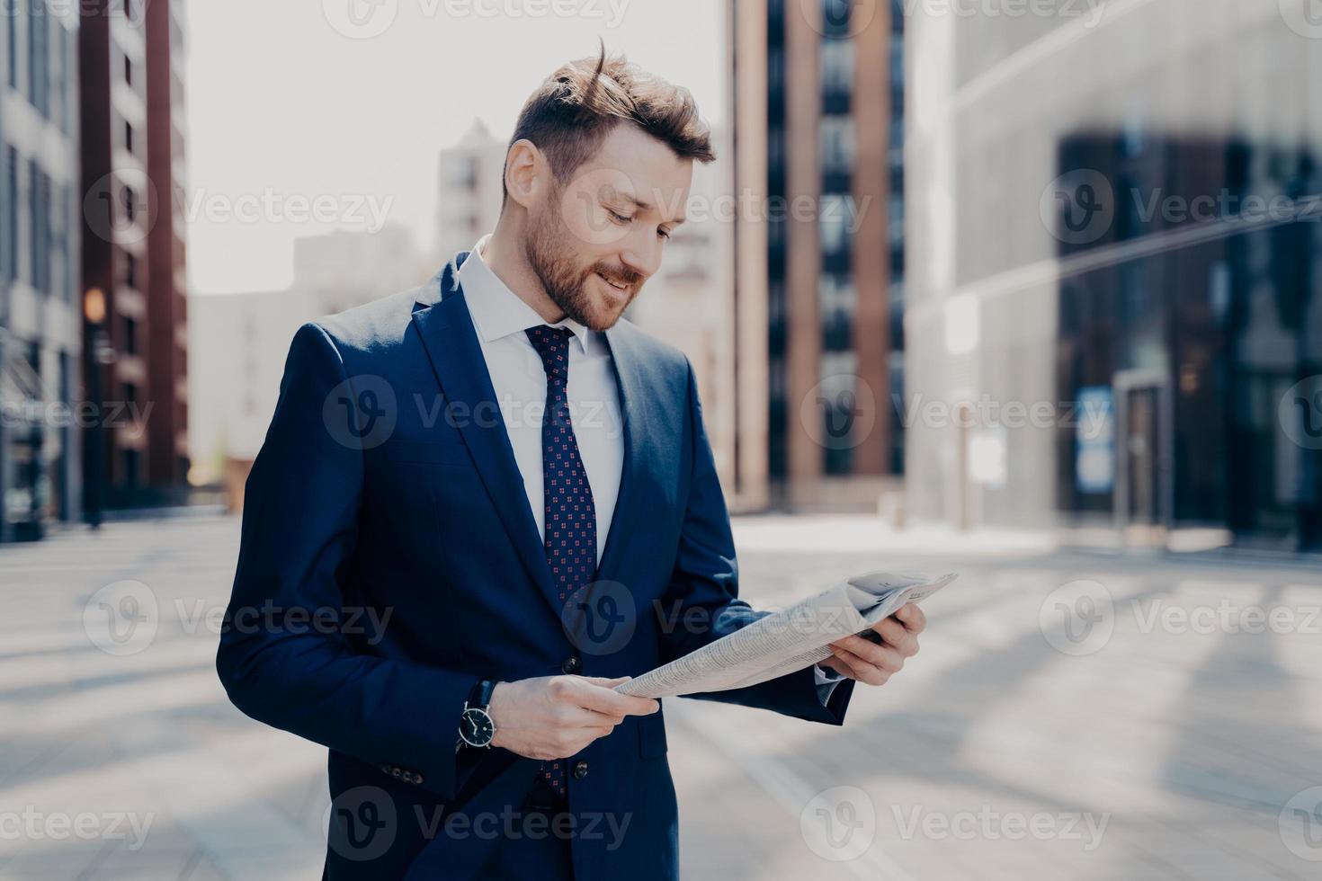 Business owner reading positive news in newspaper while walking to work photo