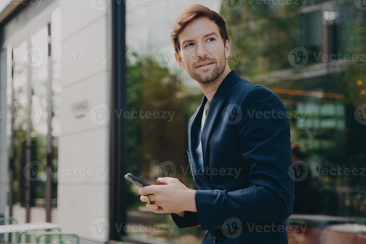 Pensive businessman holds cellular sends text messages dressed formally photo