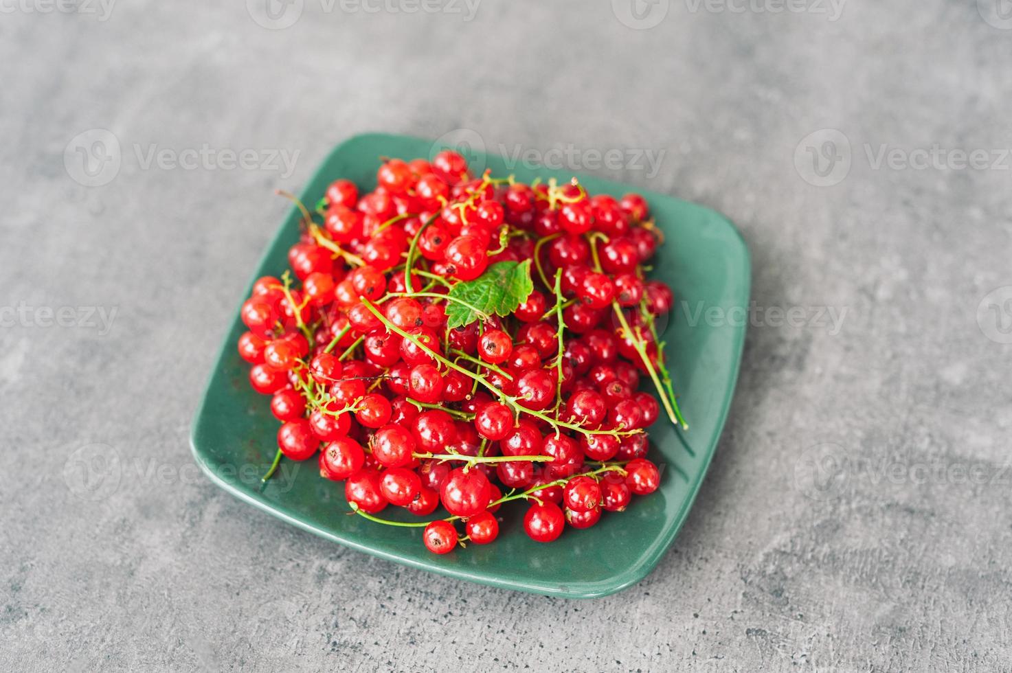 Tasty ripe red currant on plate at dark rustic table. Fresh summer berries. Fruit and vitamins. Healthy eating concept. Seasonal berries photo