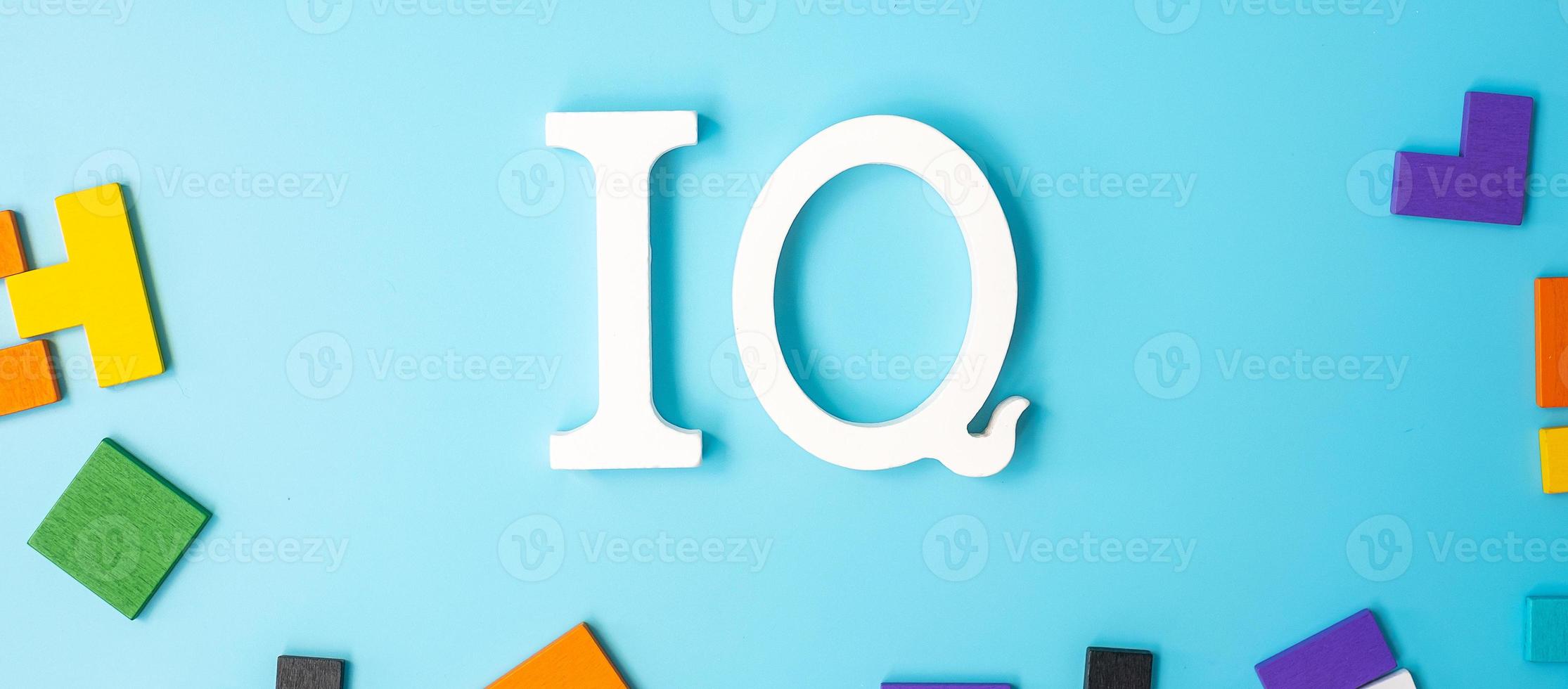 IQ text with colorful wood puzzle pieces, geometric shape block on blue background. Concept of intelligence quotient and logic thinking photo