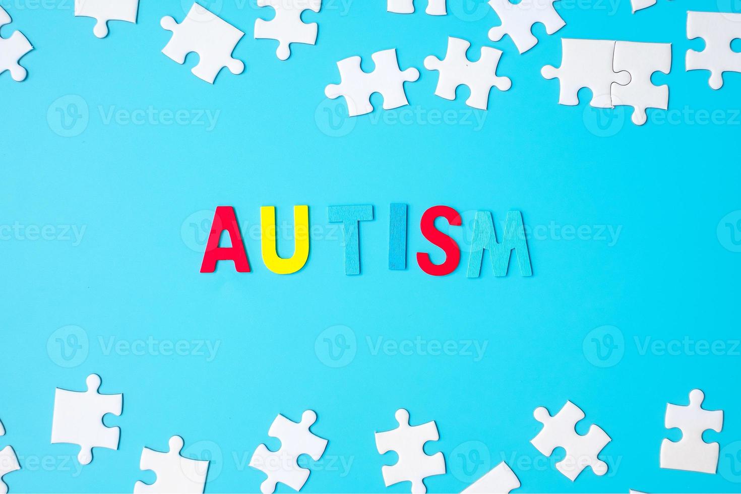 AUTISM text with white puzzle jigsaw pieces on blue background. Concepts of health, Autistic Spectrum disorder and world Autism awareness day photo