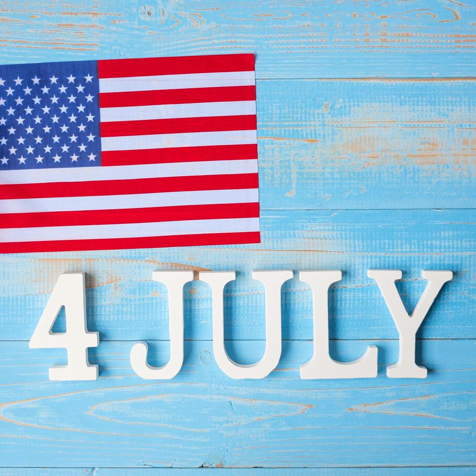 Fourth of July text and United States of America flag on wooden table background. USA holiday of Independence and celebration concepts photo