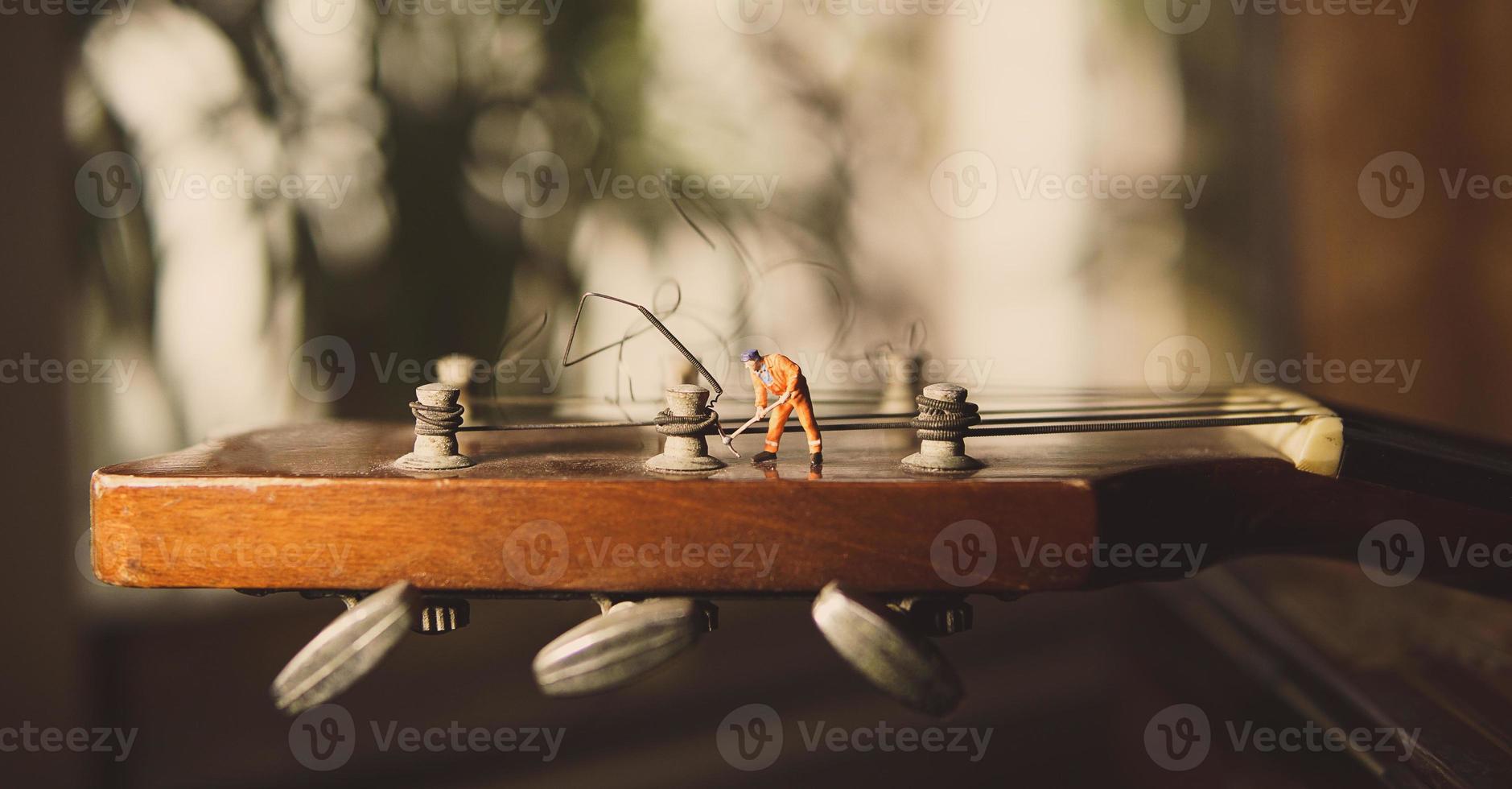 The technician worker figure fixing old guitar strings. photo