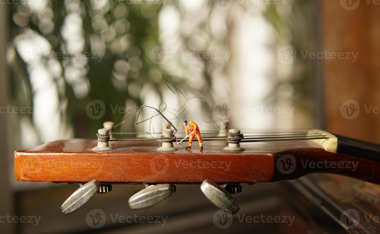 The technician worker figure fixing old guitar strings. photo