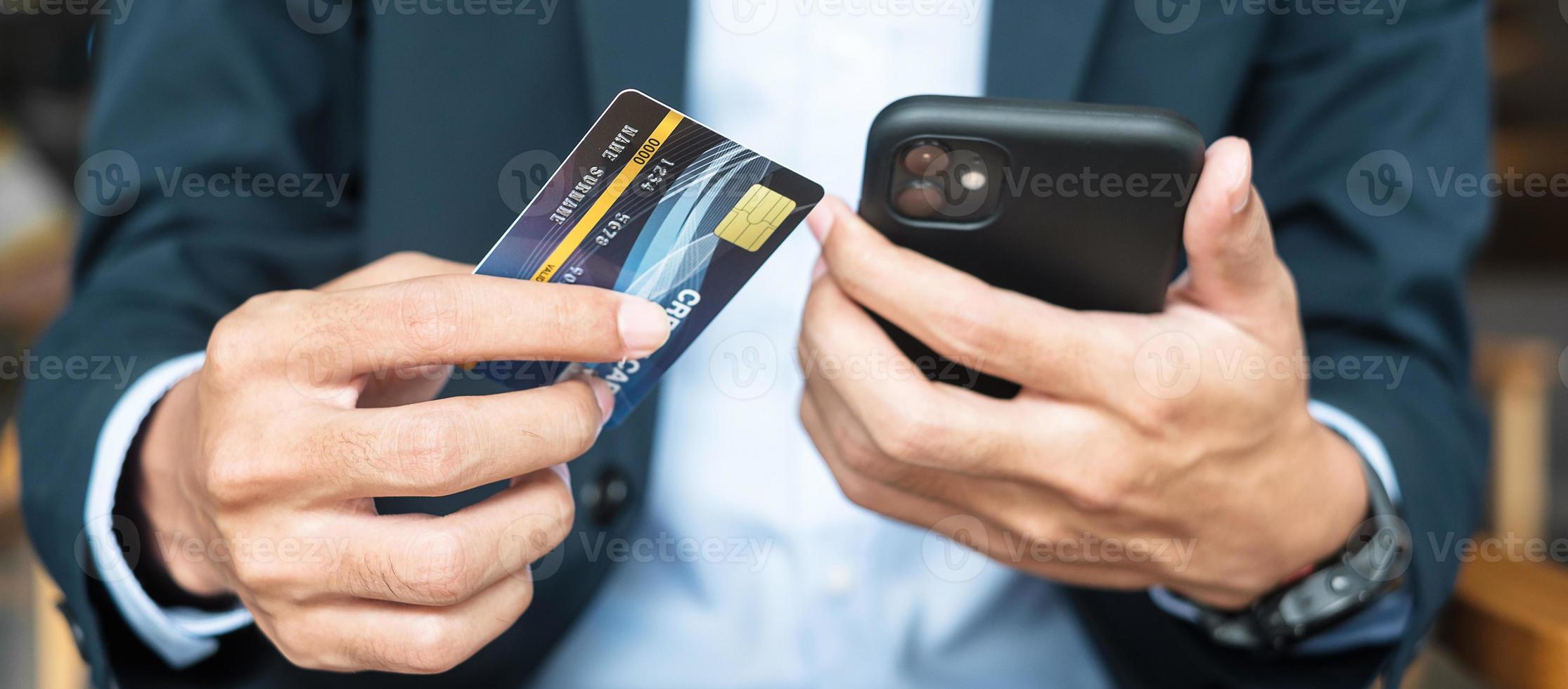 Businessman in suit holding credit card and using touchscreen smartphone for online shopping while making orders in the cafe or office .business, technology, ecommerce and online payment concept photo
