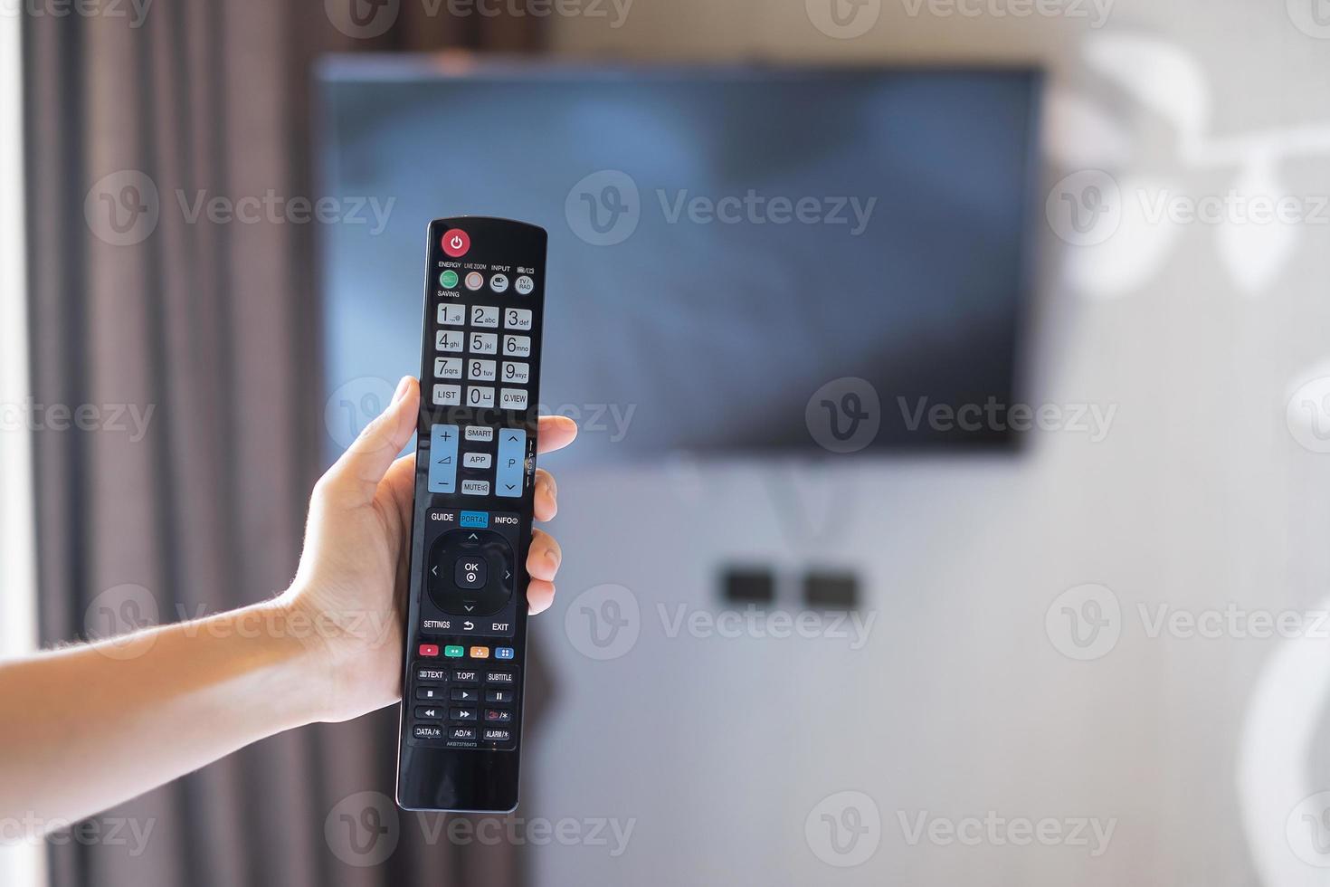 hand using remote controller for adjust Smart TV inside the modern room at home or luxury hotel photo