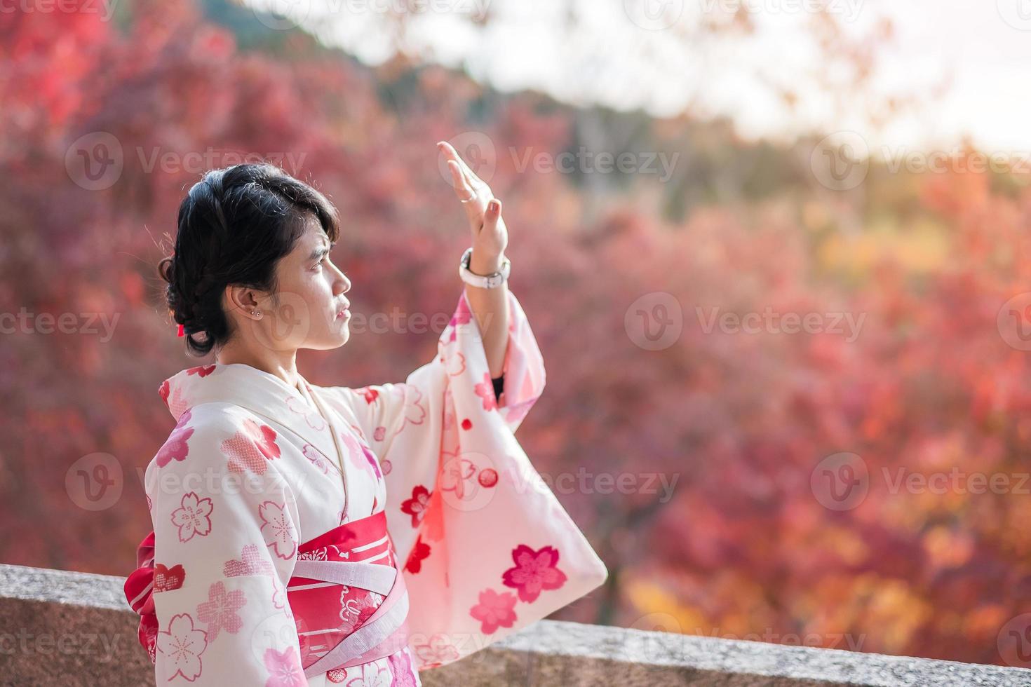 joven turista vistiendo kimono disfrutando con hojas coloridas en el templo kiyomizu dera, kyoto, japón. chica asiática con estilo de cabello en ropa tradicional japonesa en la temporada de follaje de otoño foto