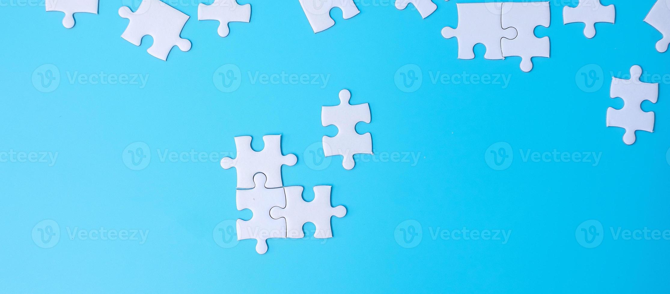 grupo de piezas de rompecabezas blancas sobre fondo azul. concepto de soluciones, misión, éxito, objetivos, cooperación, asociación, estrategia y día del rompecabezas foto