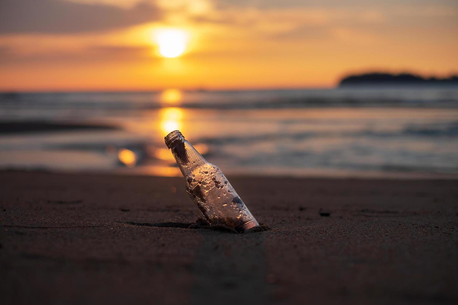 Glass Bottle garbage on the beach against sunset background. Ecology,  Environmental, pollution and Ecological problem concept photo