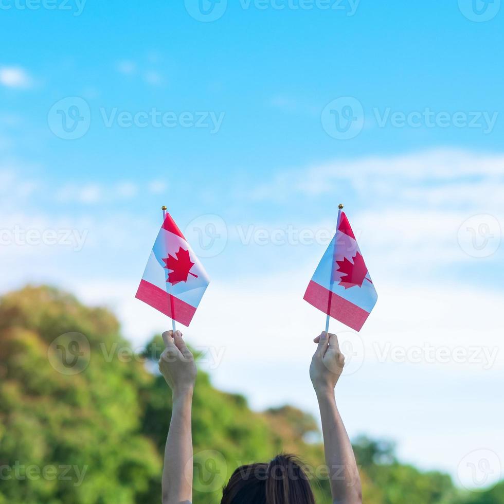 hand holding Canada flag on blue sky background. Canada Day  and happy celebration concepts photo
