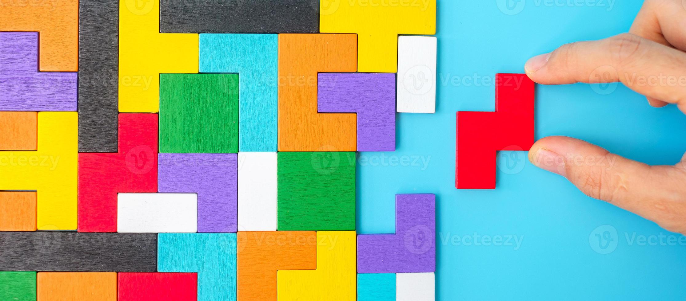 Hand connecting colorful wood puzzle pieces on blue background, geometric shape block. Concepts of logical thinking, Conundrum, solutions, rational, strategy, world logic day and Education photo