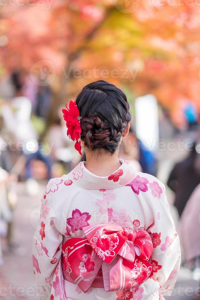 joven turista vistiendo kimono disfrutando con hojas coloridas en el templo kiyomizu dera, kyoto, japón. chica asiática con estilo de cabello en ropa tradicional japonesa en la temporada de follaje de otoño foto