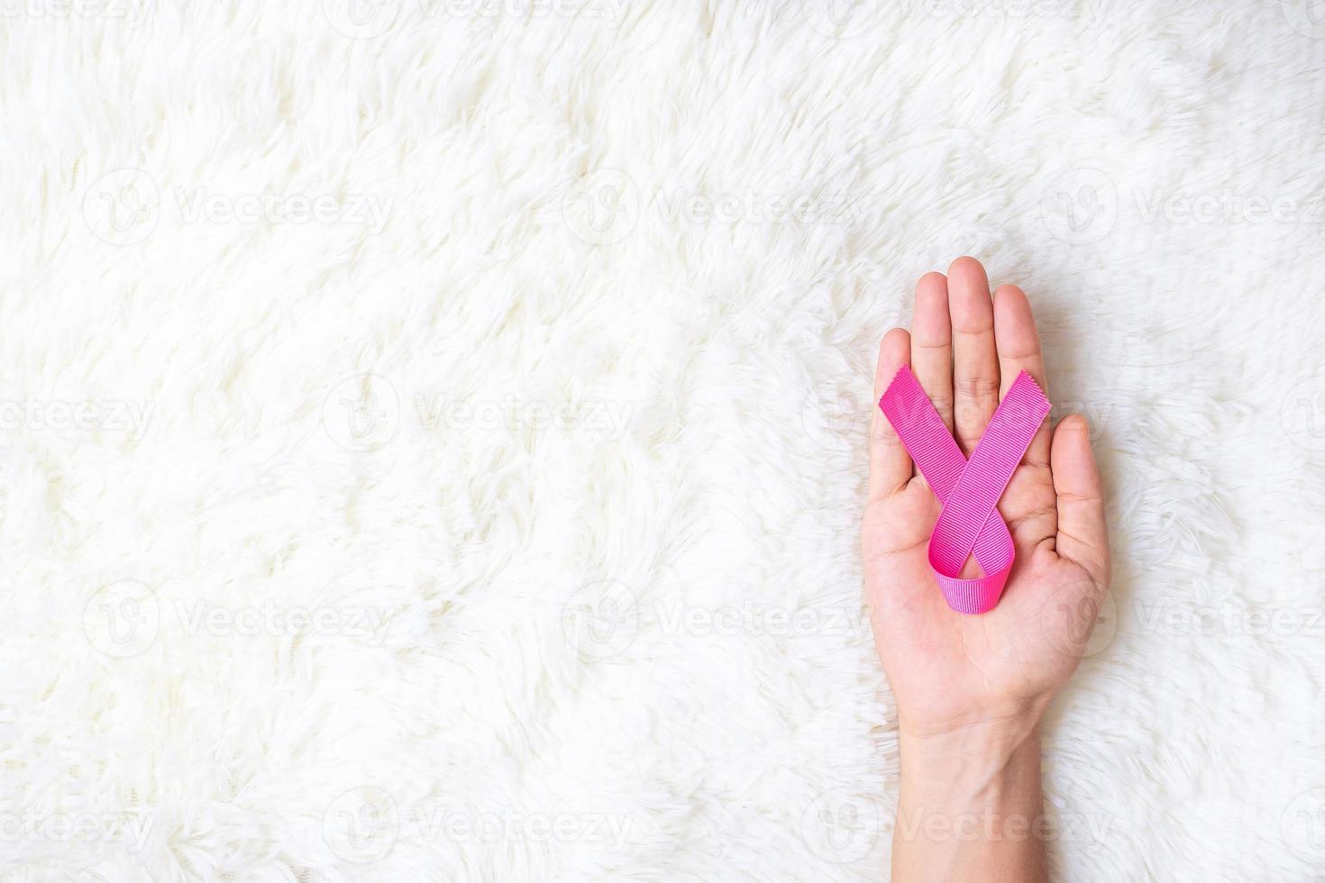 October Breast Cancer Awareness month, adult Woman  hand holding Pink Ribbon on pink background for supporting people living and illness. International Women, Mother and World cancer day concept photo